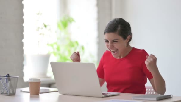 Jeune femme indienne célébrant le succès tout en utilisant un ordinateur portable au bureau - Séquence, vidéo