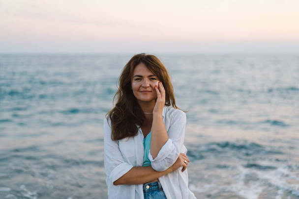 Retrato de una joven feliz sobre un fondo de hermoso mar. La chica mira el mar mágico. Libertad y felicidad - Foto, imagen