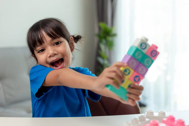 Schattig klein meisje spelen speelgoed blokken in een lichte kamer - Foto, afbeelding
