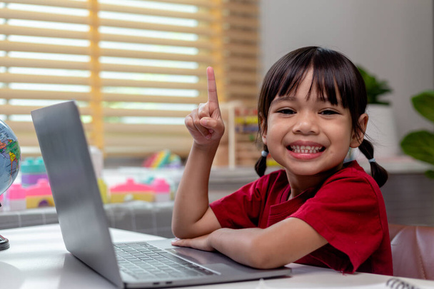 自宅の隔離中にオンライン研究ホームスクールのためのラップトップコンピュータを使用してアジアの女の子。ホームスクール,オンライン研究,家庭用隔離,オンライン学習,コロナウイルスや教育技術の概念 - 写真・画像