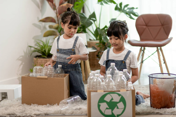 Smiling children having fun while segregating plastic bottles and paper into a bin - Foto, Imagem