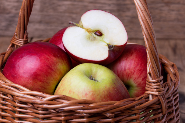 Fresh red apples in basket over wooden background - Photo, Image