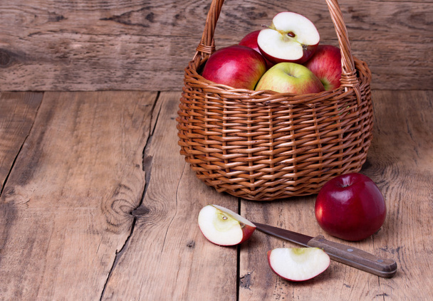 Fresh red apples in basket over wooden background - Фото, зображення