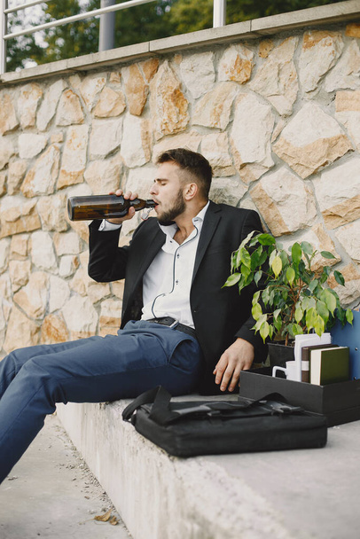 European employee got fired. He drinks alcohol from bottle. - Photo, image