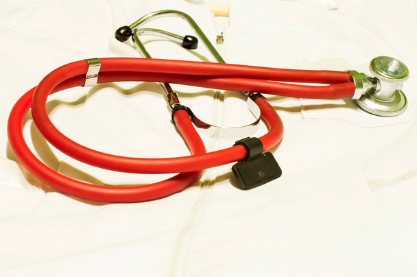 Медицинский стетоскоп красного света против белого халата
  - Фото, изображение