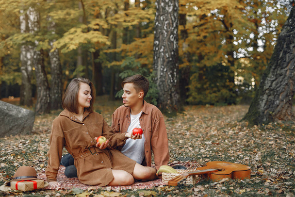 Couple in a park. Guy in a brown shirt. Golden autumn. Man with a guitar. - Foto, imagen