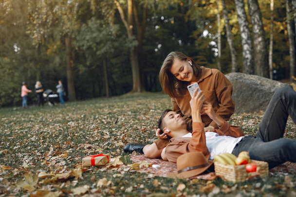 Couple in a park. Guy in a brown shirt. Golden autumn. - Fotografie, Obrázek