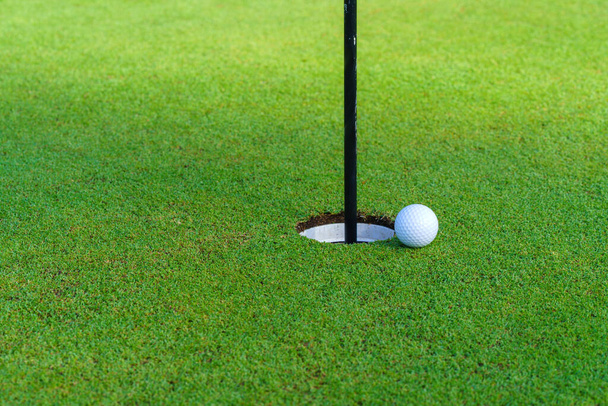 Golf piłka na zielonej trawie gotowy w pobliżu wargi kubka na boisku golfowym. - Zdjęcie, obraz