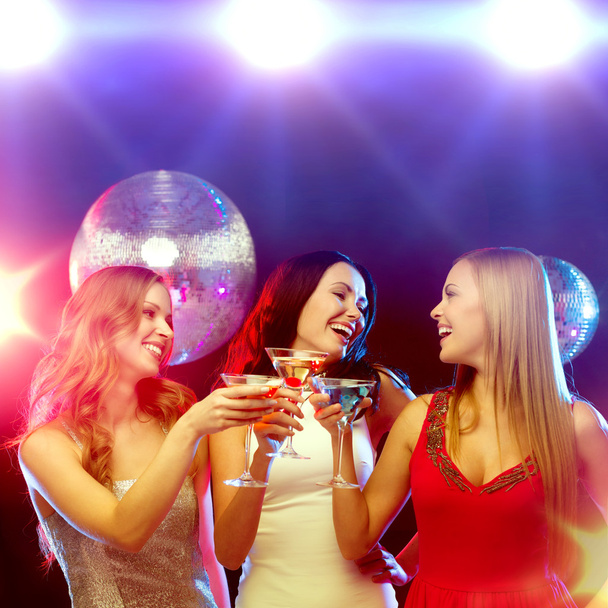 drie glimlachende vrouwen met cocktails en disco bal - Foto, afbeelding