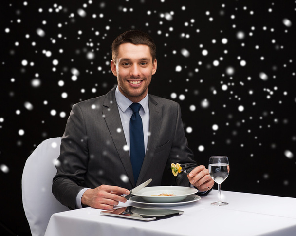 smiling man with tablet pc eating main course - Photo, image