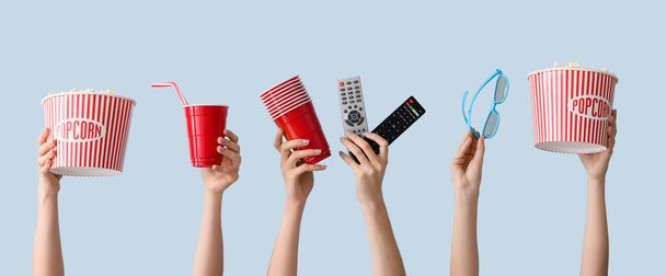 Багато рук з попкорном, чашками, пультом дистанційного керування та 3D окулярами на кольоровому фоні
 - Фото, зображення