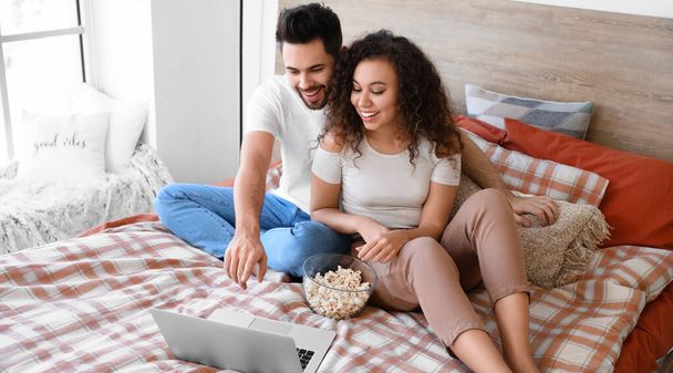 Ευτυχισμένο νεαρό ζευγάρι που βλέπει ταινία στην κρεβατοκάμαρα - Φωτογραφία, εικόνα