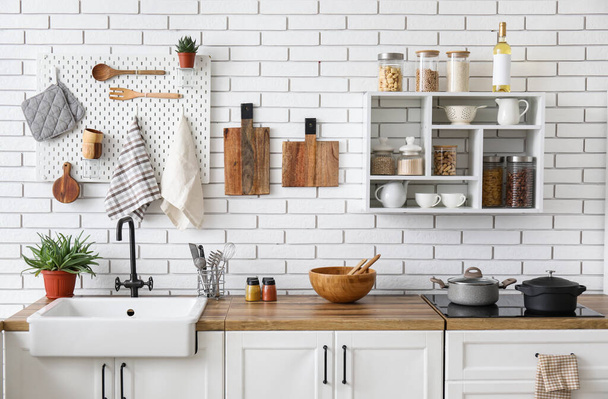 Кухонные прилавки с посудой и полками на стене из белого кирпича - Фото, изображение