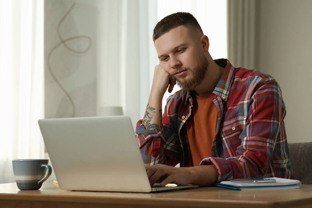 Online test. Man studying with laptop at home - Fotó, kép