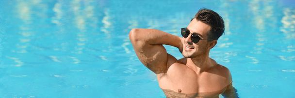 Handsome man in swimming pool on sunny day, space for text. Banner design - Photo, Image