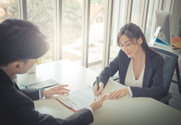 Vrouwelijke baan canidate is het ondertekenen van een arbeidscontract met HR-officier na een succesvol sollicitatiegesprek. - Foto, afbeelding