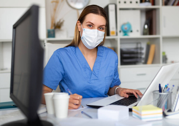 Young woman doctor assistant working in medical office using laptop computer - 写真・画像