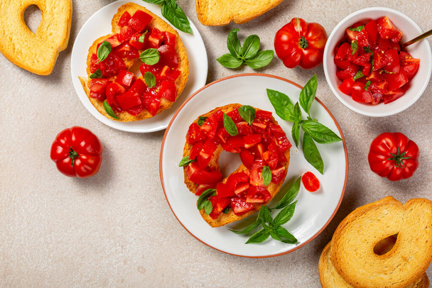 Bread, basil and tomato. Friselle or frese, a type of twice-baked bagel shaped bread from Puglia, Italy. Briefly soaked in water first, and topped with summer tomatoes and olive oil. Italian summer food concept. - Photo, Image
