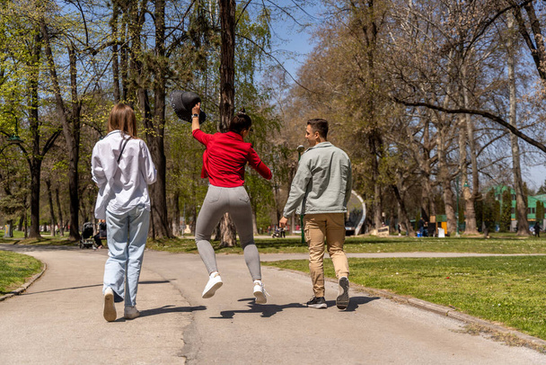 Χαρούμενοι νεαροί φίλοι περπατούν στο πάρκο. Περνάμε χρόνο μαζί και περνάμε καλά. - Φωτογραφία, εικόνα