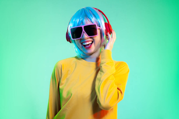 Happy young asian women in headphones isolated on neon green backgrounds. Human emotions, facial expression concept - Foto, immagini