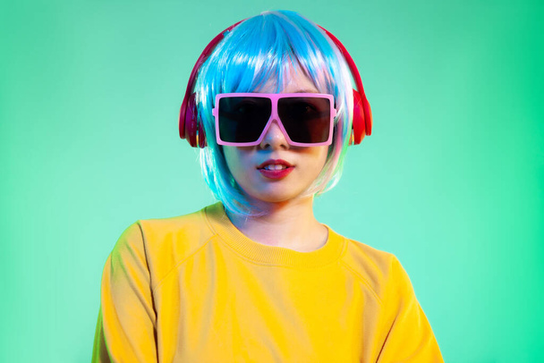 young asian women in red headphones posing isolated on neon green backgrounds. Human emotions, facial expression concept - 写真・画像