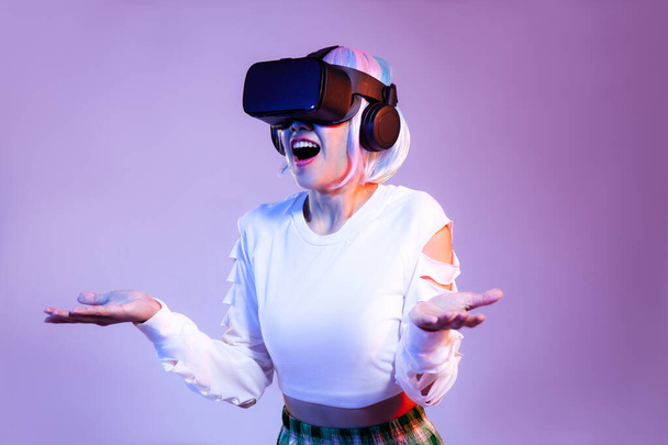 Surprised Young asian woman in white sweatshirt wearing black vr headset watching playing and hand touching on the purple background. Metaverse concept - Valokuva, kuva