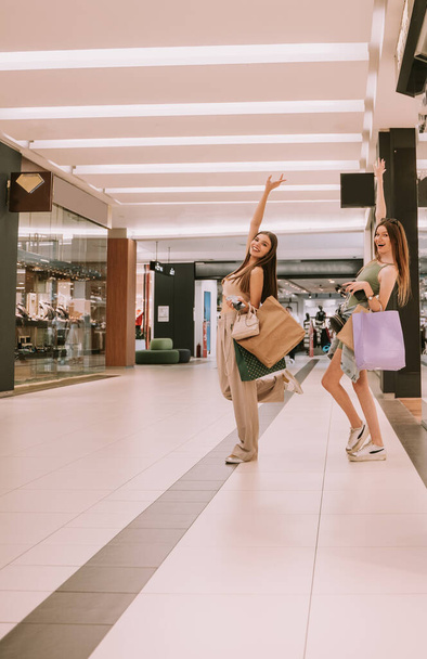 Δύο όμορφα κορίτσια διασκεδάζουν στο εμπορικό κέντρο. - Φωτογραφία, εικόνα