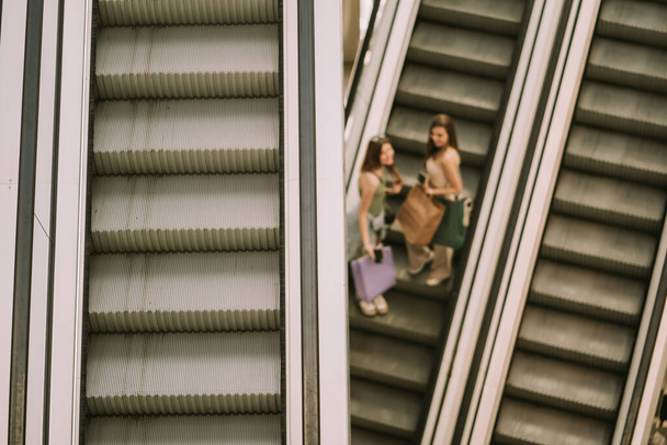 Zamazane, dwie ładne dziewczyny schodzą na schodach w centrum handlowym - Zdjęcie, obraz