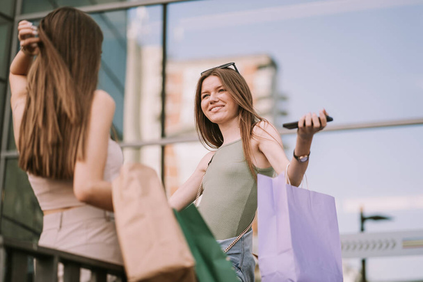 Lähikuva kaksi söpöä tyttöä seisoo ulkona ostoskassit - Valokuva, kuva