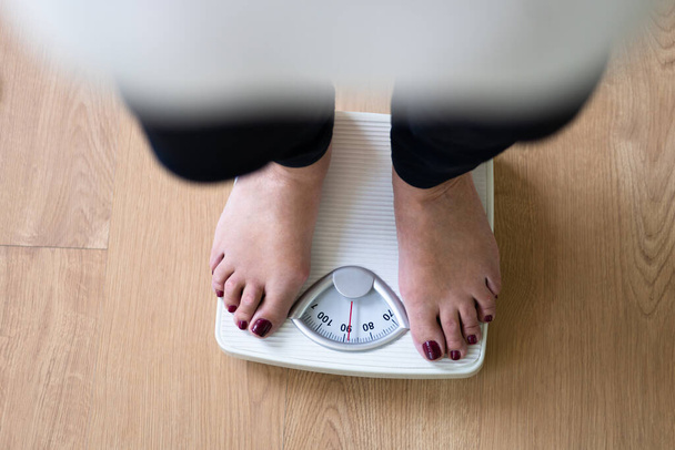 Low Section Of A Person Standing On Weighing Scale - Foto, Imagen