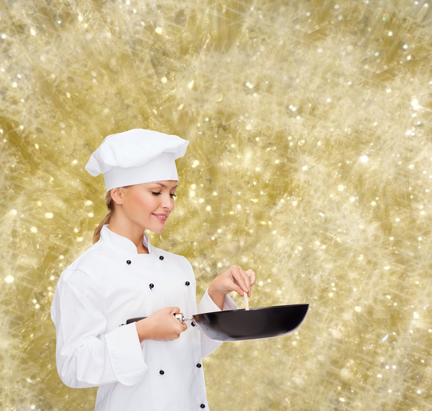 smiling female chef with pan and spoon - Valokuva, kuva