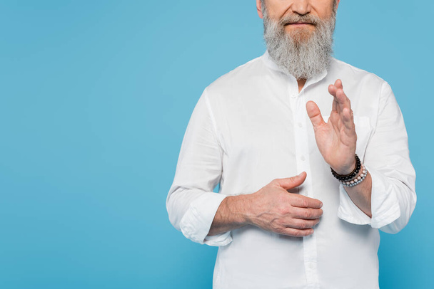 vista ritagliata di allenatore guru con barba grigia mostrando gesto benedizione isolato su blu - Foto, immagini