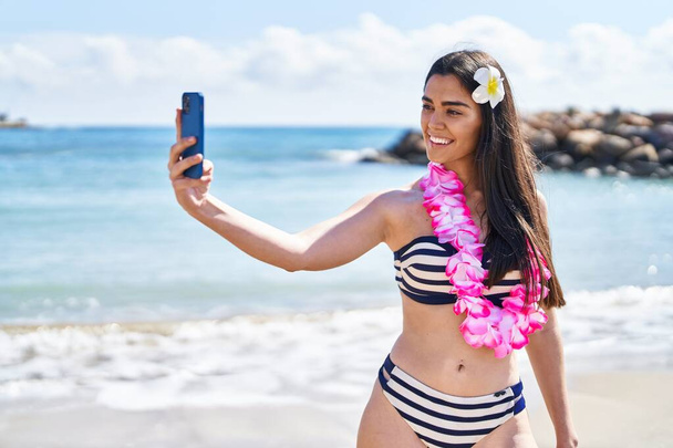 Young hispanic woman wearing bikini make selfie by smartphone at seaside - Фото, зображення