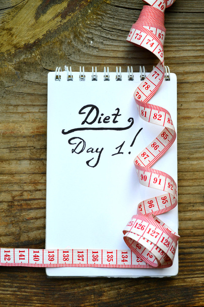 Diet concept with a notebook and red measuring tape on wooden table - Photo, Image