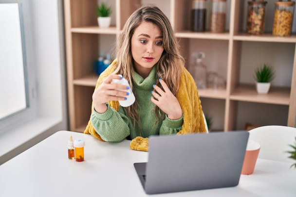 Young woman holding pills having telemedicine at home - Foto, imagen