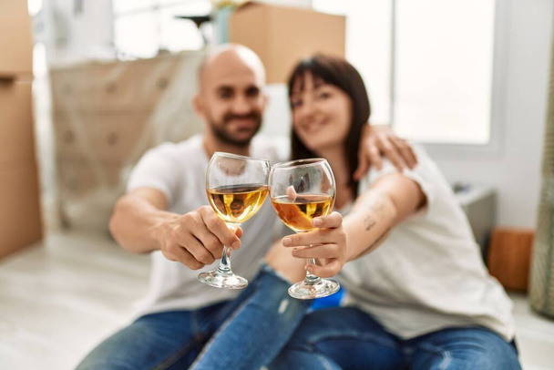 Junges hispanisches Paar lächelt glücklich und stößt mit Champagner auf sein neues Zuhause an. - Foto, Bild