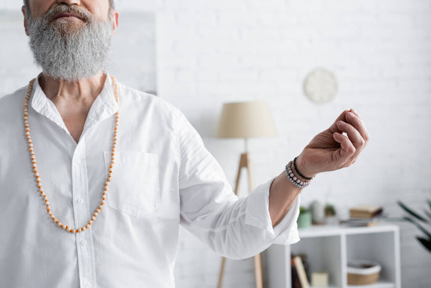 vista ritagliata di uomo guru in perline che mostrano mudra mento durante la meditazione a casa - Foto, immagini