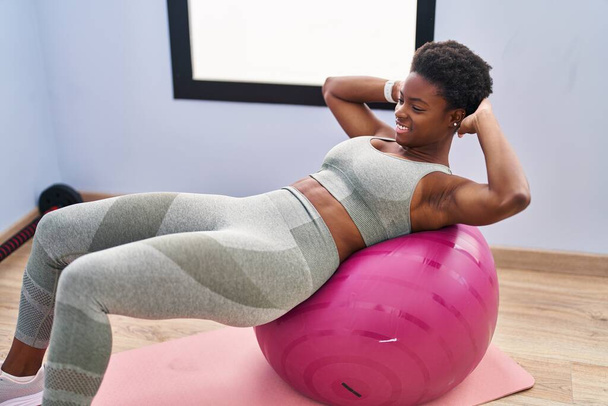 afro-américaine femme souriant entraînement confiant abs exercice au centre sportif - Photo, image