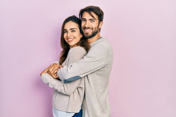 Молода пара іспаномовних в повсякденному одязі, дивлячись на бік, розслабляє профільну позу з природним обличчям і впевнено посміхається
.  - Фото, зображення