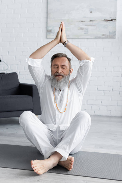 guru sênior homem meditando em pose fácil com as mãos levantadas e mudra anjani - Foto, Imagem