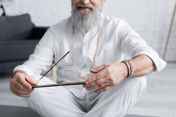 vista parcial del hombre gurú en ropa blanca y pulseras de cuentas con palo de aroma - Foto, imagen