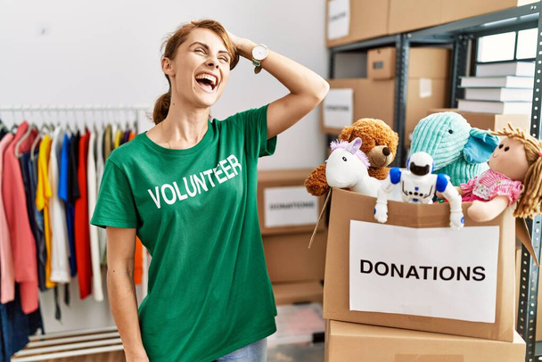 Beautiful caucasian woman wearing volunteer t shirt at donations stand smiling confident touching hair with hand up gesture, posing attractive and fashionable  - Photo, Image