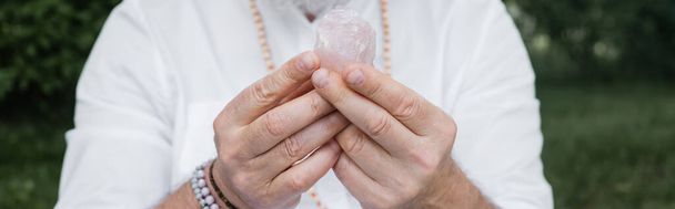 обрезанный вид размытого гуру, держащего селенит кристалл на открытом воздухе, баннер - Фото, изображение