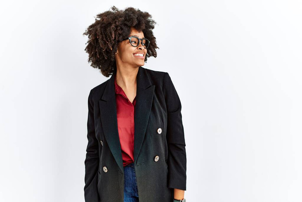 African american woman with afro hair wearing business jacket and glasses looking away to side with smile on face, natural expression. laughing confident.  - Foto, Imagen
