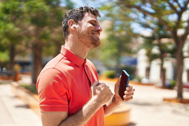 Young hispanic man smiling confident using smartphone at park - Foto, Imagen