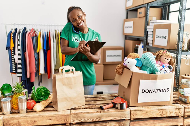 Jovem africana americana voluntária mulher sorrindo feliz trabalhando no centro de caridade. - Foto, Imagem