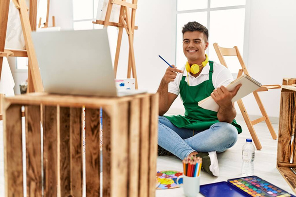 Jovem hispânico sorrindo confiante ter aula de desenho on-line no estúdio de arte - Foto, Imagem