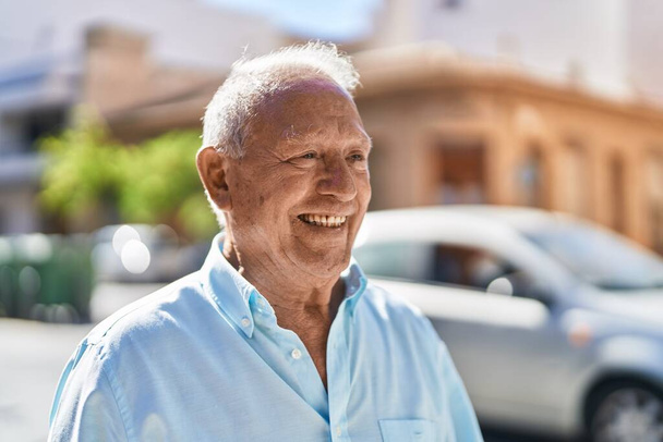 Homem de cabelos grisalhos sênior sorrindo confiante em pé na rua - Foto, Imagem