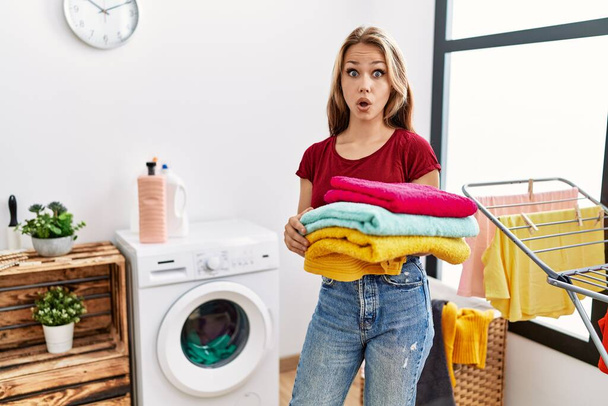 きれいな洗濯を持っている若い白人女性は怖がって、驚きのために口を開けて驚いて,不信の顔  - 写真・画像