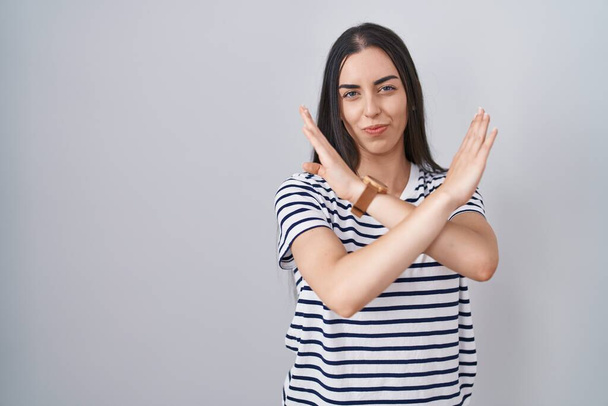 Молода брюнетка жінка в смугастій сорочці відмовляється перетинати руки, роблячи негативний знак, розлючене обличчя
  - Фото, зображення